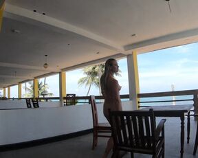 Nude lady ambles on the balcony disregarding the ocean