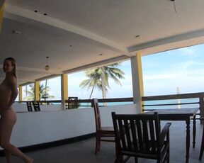 Nude lady ambles on the balcony disregarding the ocean
