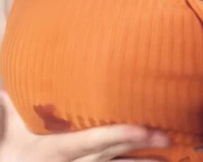 A fat woman in an orange blouse. Lactation through clothes and display of large milk boobs