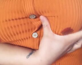 A fat woman in an orange blouse. Lactation through clothes and display of large milk boobs