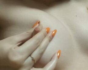 A naughty young girl's finger with a bright manicure play with her nipples
