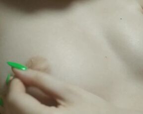 A naughty young girl's finger with a bright manicure play with her nipples