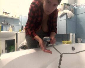 The housewife washes the bathtub. Her boobs are peeking out of her unbuttoned shirt