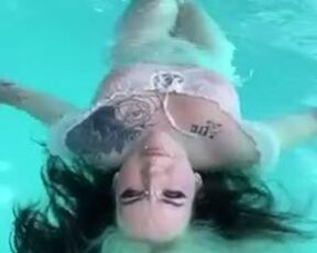 Goth girl floats in the pool with her tits out