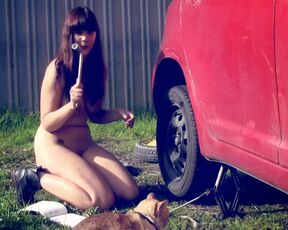 Naked girl at work. Changing a tire on the car shaking her big boobs