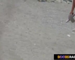 Nude lady is lying on the beach, while a horny voyeur is watching her shaved pussy
